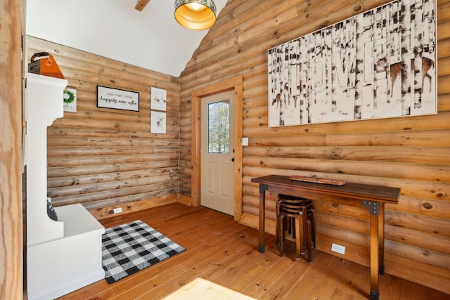 foyer entrance with vaulted ceiling, hardwood / wood-style flooring, and log walls