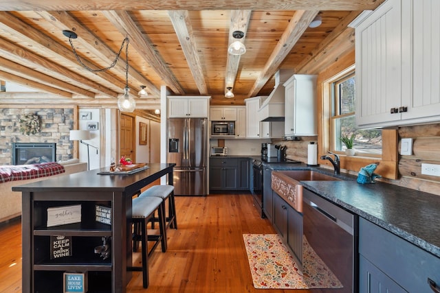 kitchen featuring premium range hood, a sink, dark countertops, stainless steel appliances, and wooden ceiling