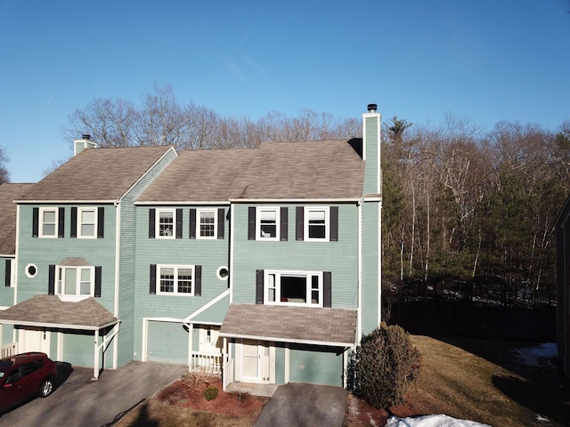 view of front of house with an attached garage, driveway, and a chimney