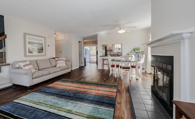 living area featuring a fireplace, baseboards, a ceiling fan, and wood finished floors