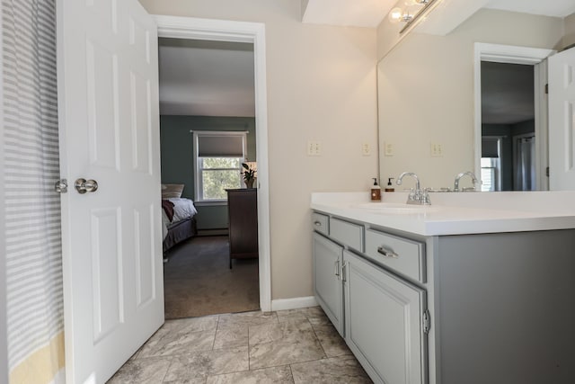 bathroom with connected bathroom, vanity, and baseboards