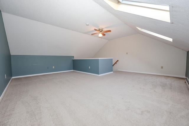 additional living space with baseboards, lofted ceiling with skylight, carpet, and ceiling fan