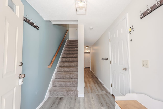 staircase featuring wood finished floors and baseboards