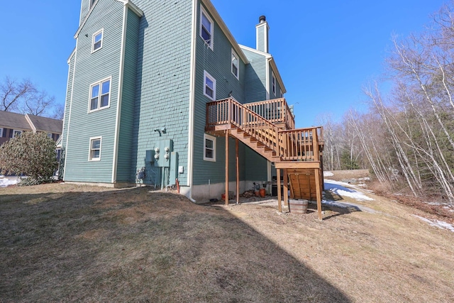 rear view of property with stairway, a lawn, a chimney, and a deck