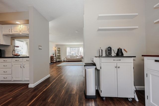 kitchen featuring dark countertops, white cabinets, dark wood-type flooring, and baseboards