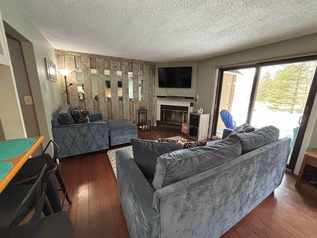 living area featuring a glass covered fireplace, a textured ceiling, and wood finished floors