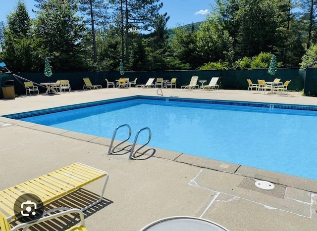 community pool with a patio and fence