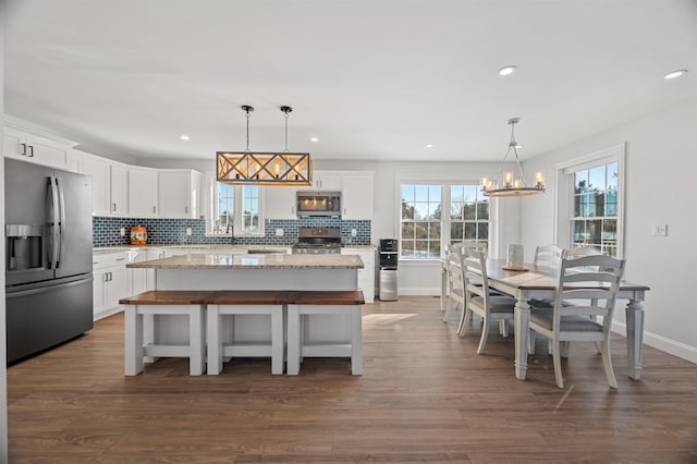 kitchen with decorative backsplash, dark wood-style floors, a kitchen island, and stainless steel appliances