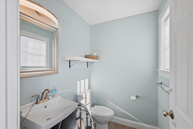 bathroom featuring baseboards, toilet, wood finished floors, and vanity