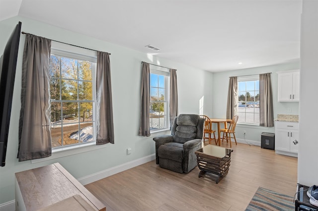 living area featuring light wood-type flooring, visible vents, and baseboards