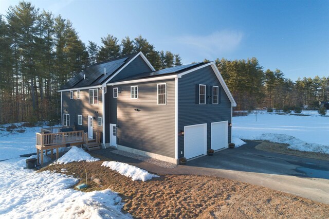 view of snow covered exterior with a garage, a deck, and driveway