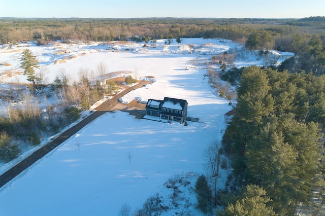 snowy aerial view featuring a wooded view