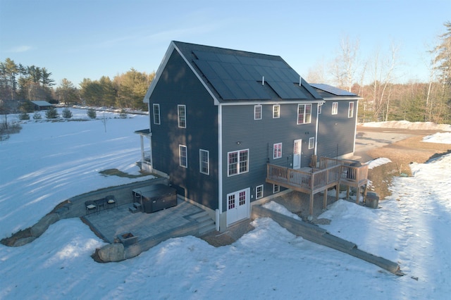 snow covered property featuring a wooden deck and solar panels