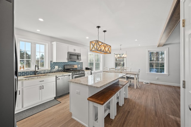 kitchen featuring light wood finished floors, backsplash, a center island, stainless steel appliances, and a sink