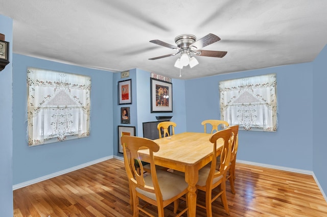 dining area featuring wood finished floors, baseboards, and ceiling fan