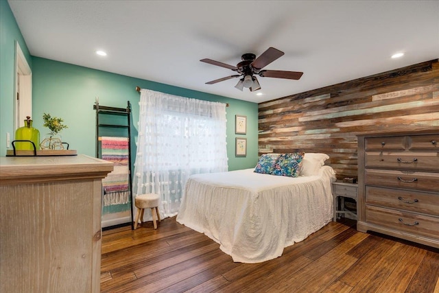 bedroom with wooden walls, recessed lighting, and dark wood-style floors