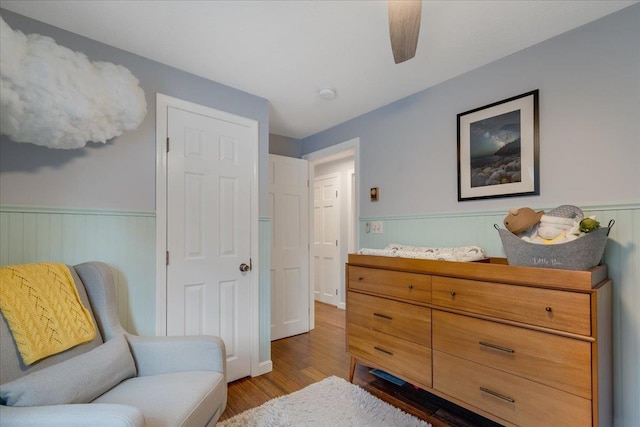 sitting room featuring ceiling fan, wood finished floors, and wainscoting