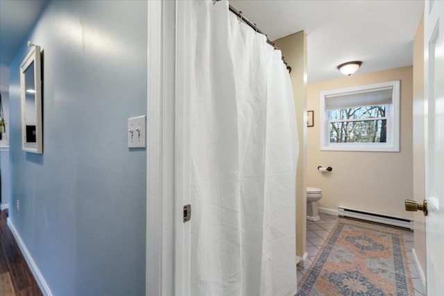 bathroom featuring toilet, baseboards, and a baseboard radiator