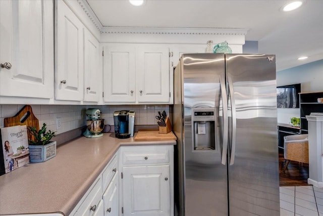 kitchen featuring backsplash, white cabinetry, light countertops, and stainless steel refrigerator with ice dispenser