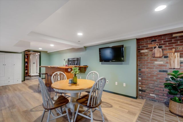 dining space with recessed lighting, brick wall, and light wood-type flooring