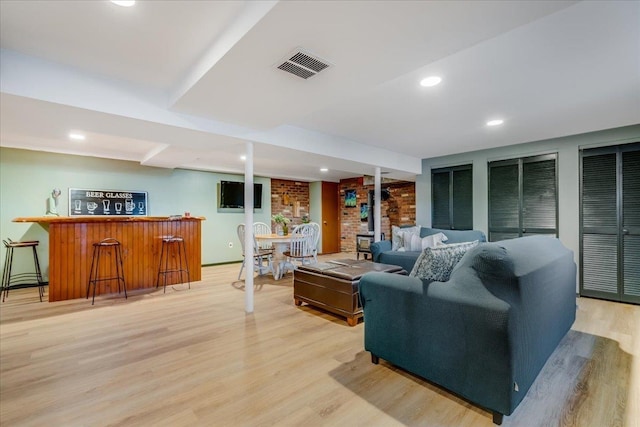 living area with light wood finished floors, visible vents, a dry bar, recessed lighting, and a wood stove