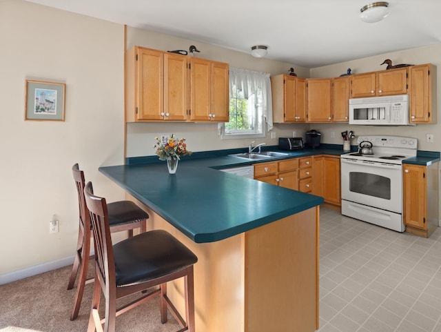 kitchen featuring dark countertops, white appliances, a breakfast bar, and a sink