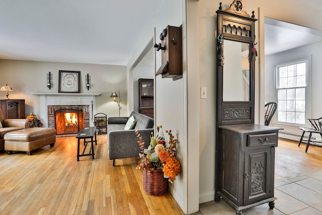 living room featuring a baseboard heating unit, a fireplace, and light wood-type flooring