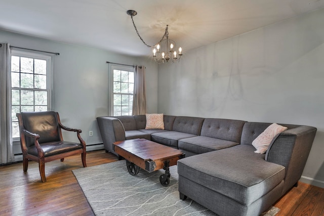 living area featuring baseboards, wood-type flooring, and a notable chandelier