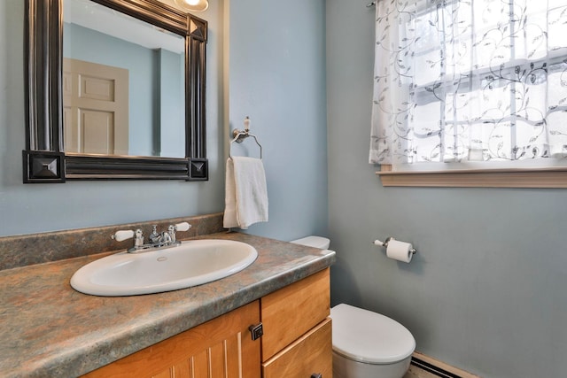 bathroom featuring vanity, toilet, and baseboard heating