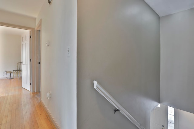 hallway with an upstairs landing and light wood finished floors