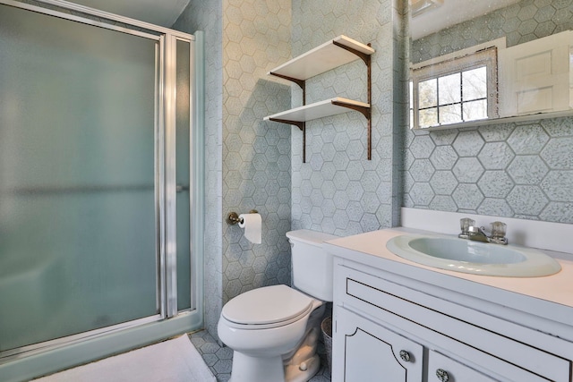 full bathroom with tile patterned flooring, toilet, vanity, a stall shower, and tile walls