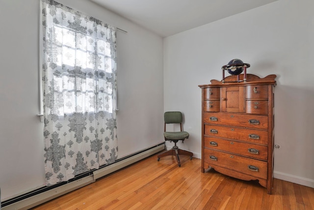 interior space with baseboards, a baseboard heating unit, and light wood-style floors