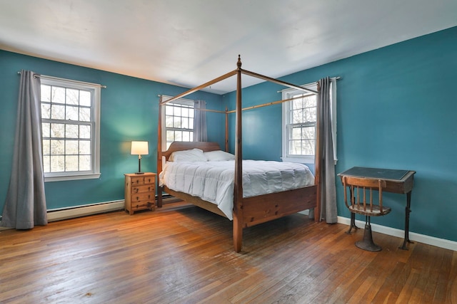 bedroom with a baseboard heating unit, baseboards, and wood-type flooring