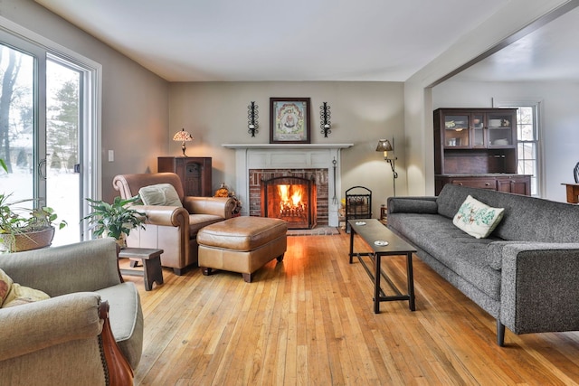 living room featuring light wood-type flooring and a brick fireplace