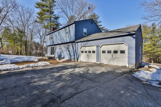 view of home's exterior featuring aphalt driveway, an attached garage, and a chimney