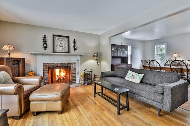 living room with a brick fireplace and light wood-style floors