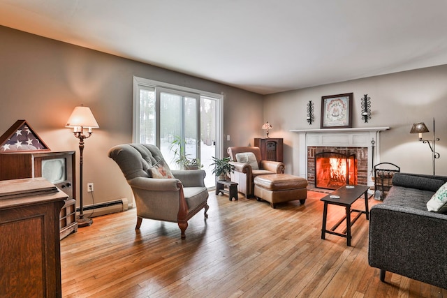 living area with wood-type flooring, baseboard heating, and a brick fireplace