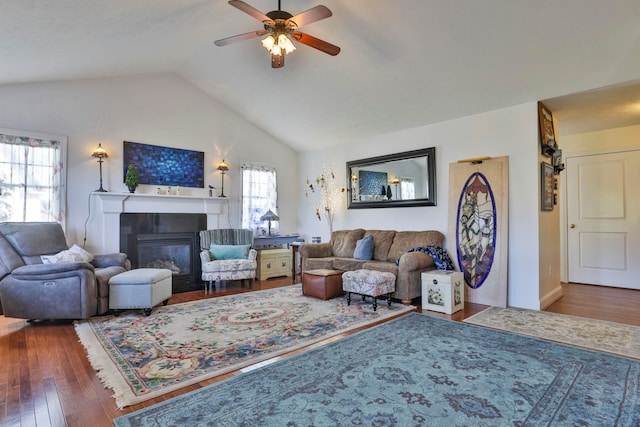 living room featuring a glass covered fireplace, ceiling fan, lofted ceiling, and wood finished floors