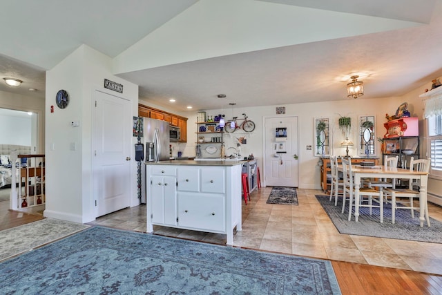 kitchen with baseboards, decorative light fixtures, vaulted ceiling, appliances with stainless steel finishes, and brown cabinetry