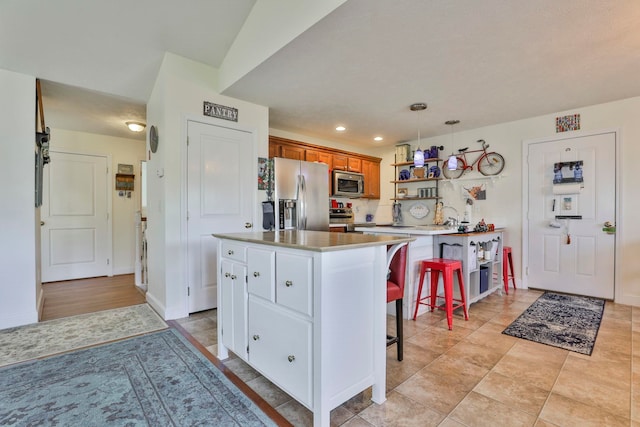 kitchen with a center island, recessed lighting, appliances with stainless steel finishes, a kitchen breakfast bar, and brown cabinetry