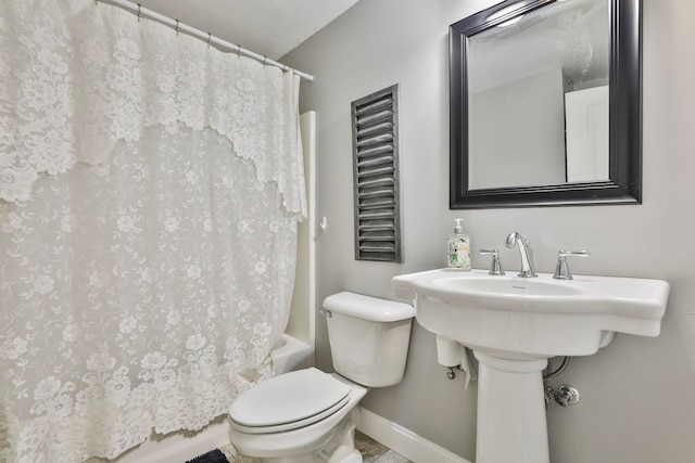 bathroom featuring baseboards, shower / bath combo with shower curtain, and toilet