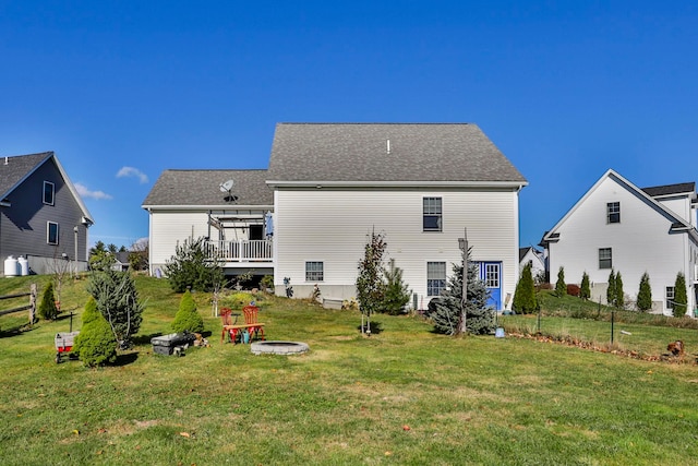 rear view of house featuring a lawn, an outdoor fire pit, and fence