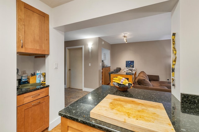 kitchen featuring dark stone countertops, baseboards, a peninsula, and open floor plan