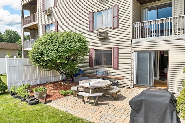 view of patio featuring a wall unit AC, a grill, and fence