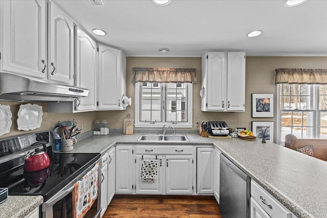 kitchen featuring dark wood-type flooring, under cabinet range hood, stainless steel appliances, white cabinetry, and a sink