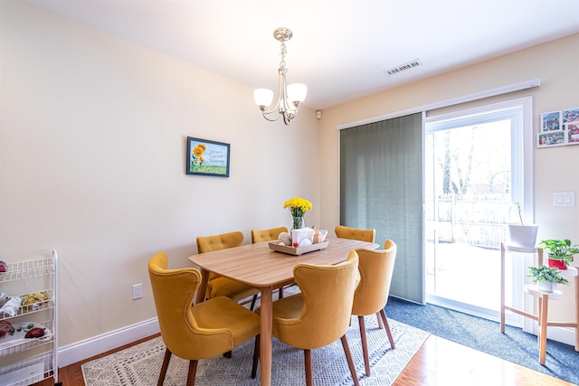 dining area with wood finished floors, a notable chandelier, baseboards, and visible vents