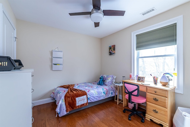 bedroom featuring a ceiling fan, wood finished floors, visible vents, and baseboards