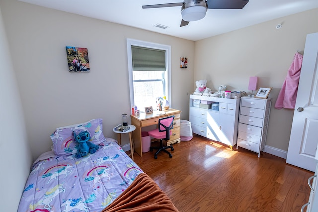 bedroom featuring ceiling fan, visible vents, baseboards, and wood finished floors