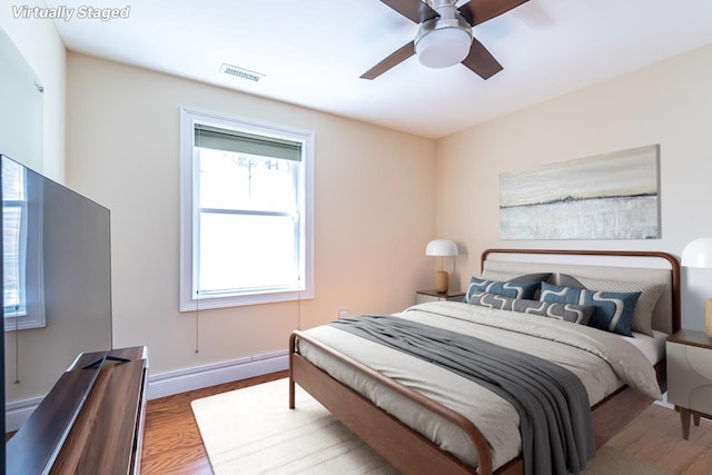 bedroom featuring a ceiling fan, wood finished floors, visible vents, and baseboards