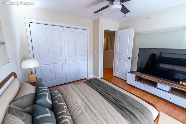 bedroom featuring a closet, baseboards, wood finished floors, and a ceiling fan